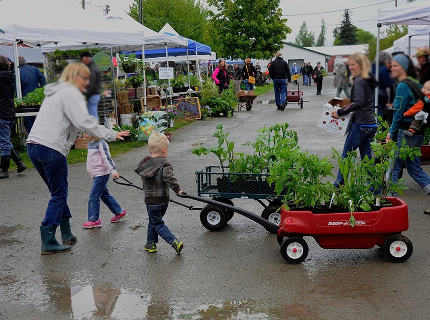 woman with kids and wagons filled with plants